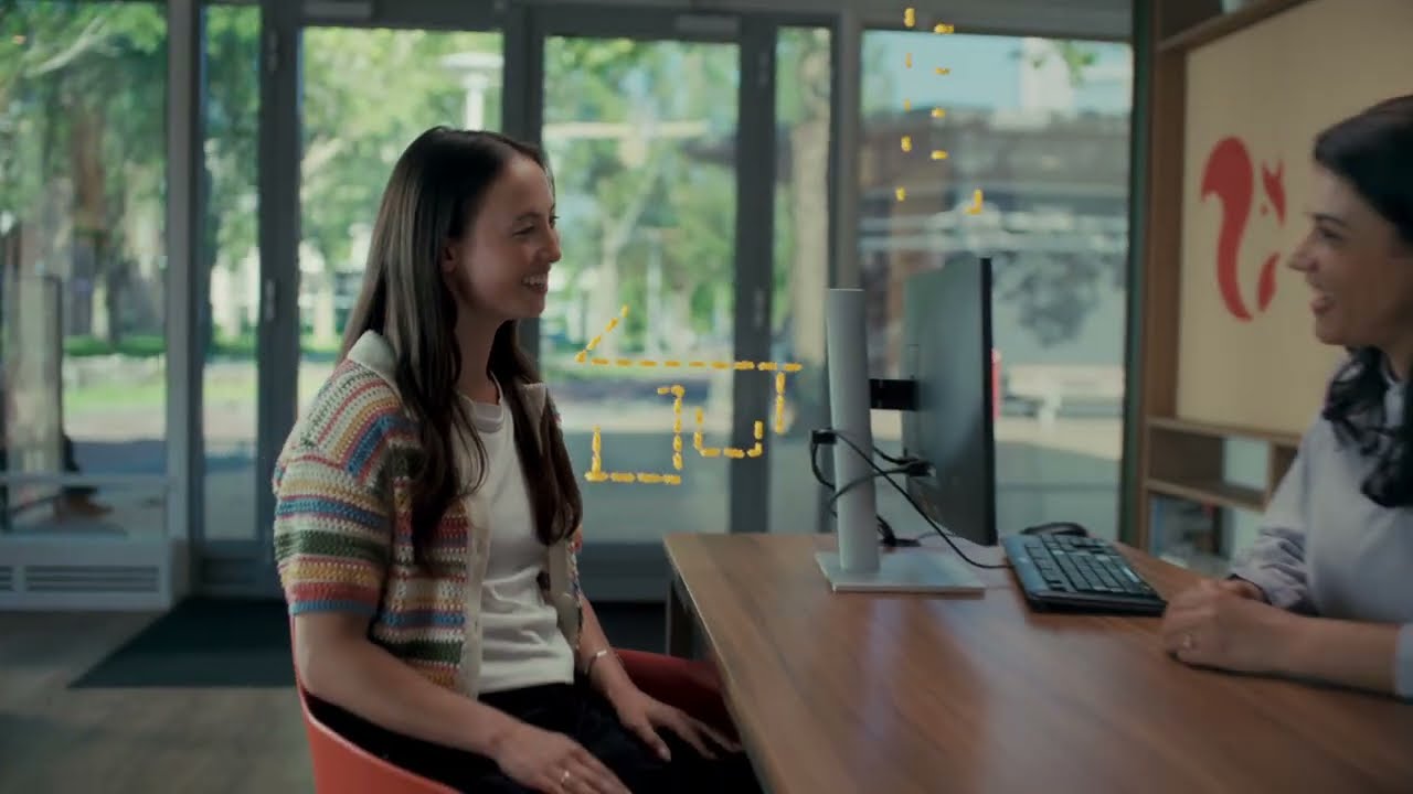 Two people talk at a desk in an ASN Bank office